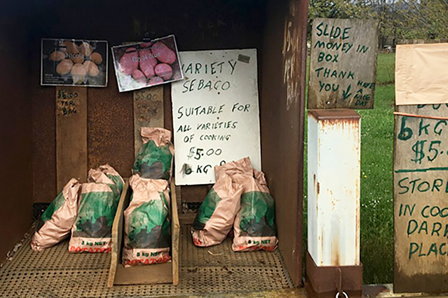 A small roadside stall near a farm selling locally grown produce and food.