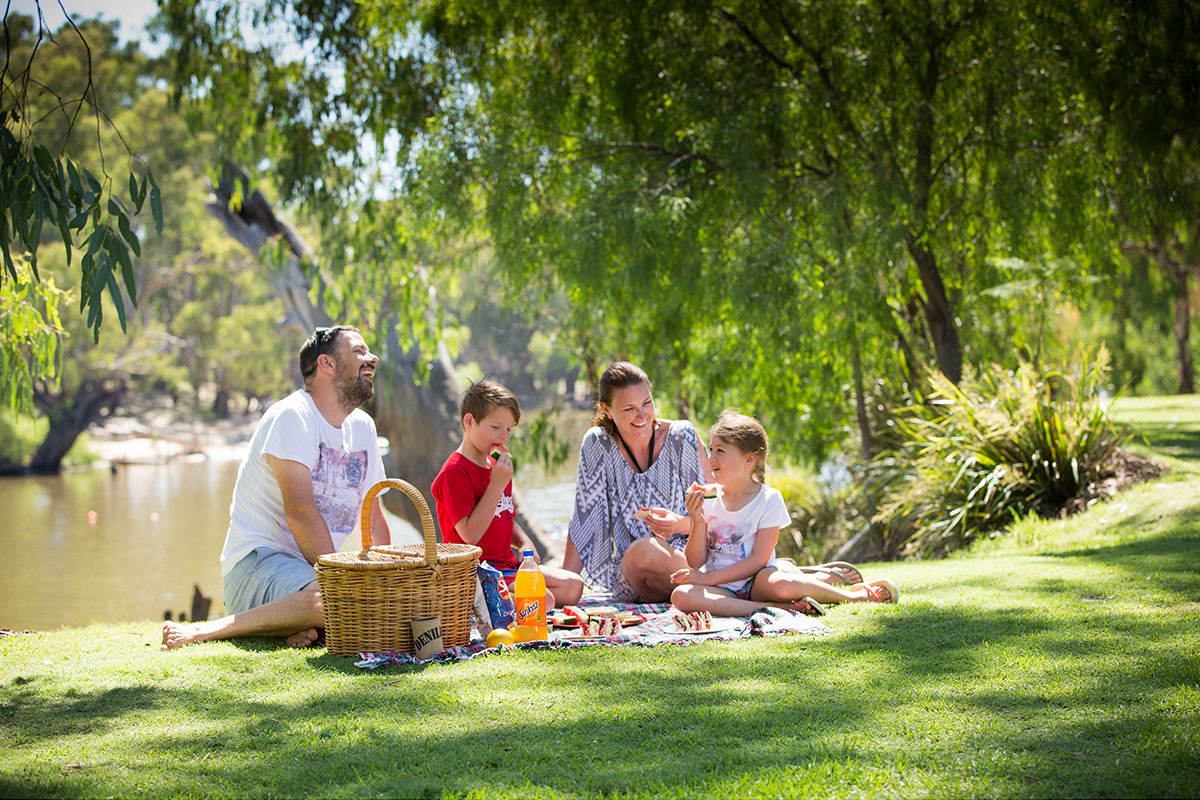 Family enjoying a picnic by the Edward River, Deniliquin in the state's Riverina Murray Region. Credit: Destination NSW