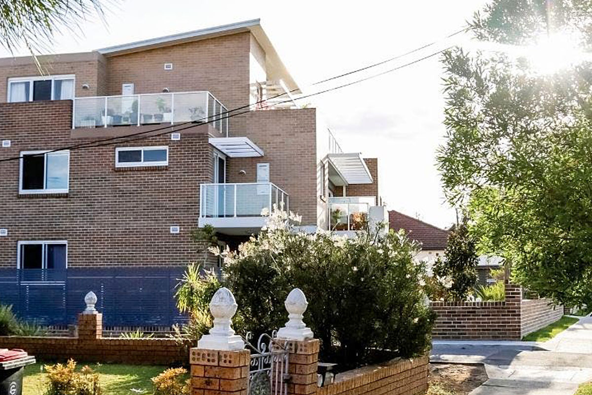 Residential street with unit block next to house.