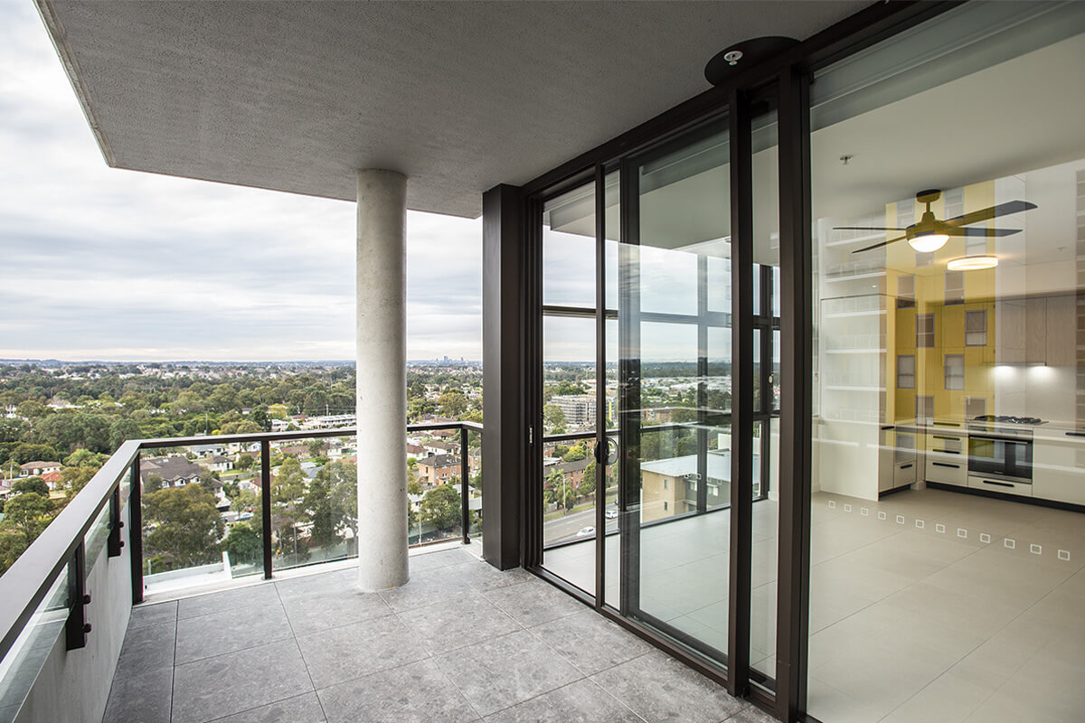 A mid- to high-rise residential apartment balcony overlooking trees and buildings.