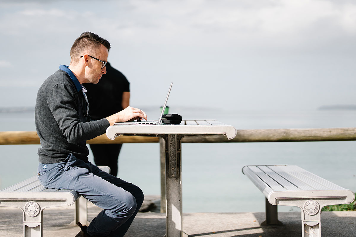 Man sitting at a bench using his laptop